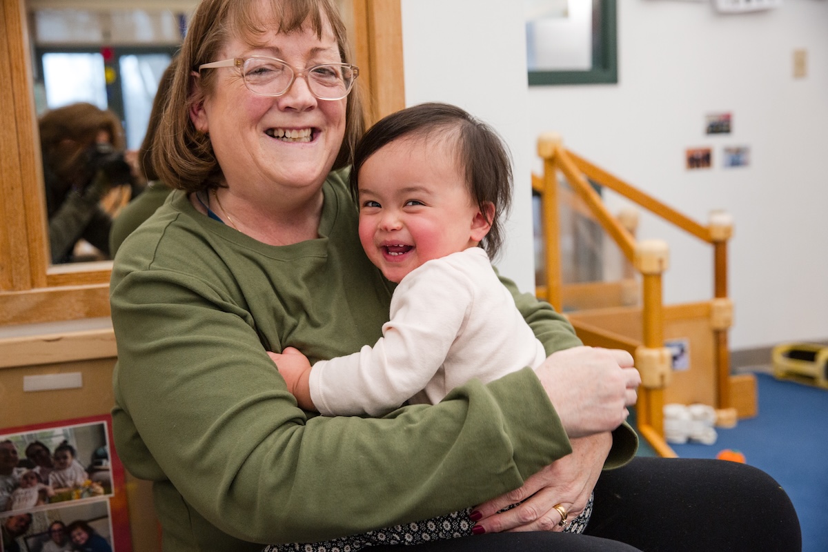 a teacher holding a child in a classroom